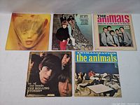 Top view of five vinyl record album covers including The Animals and The Rolling Stones.
