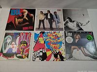 Top view photo showing 6 vinyl LP albums arranged in two rows of three. Albums include Billy Idol's Rebel Yell, Huey Lewis and the News' Fore!, and Tina Turner's Private Dancer among others.