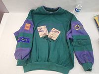Front view of green and purple sweatshirt showing front graphics and overall condition