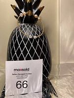 Two gold-tone adjustable bangles each with white freshwater pearls at the ends displayed on a decorative black and white pineapple stand.