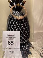 Front angled view of rose gold-tone adjustable bangle with three freshwater pearls, displayed on a decorative black and white pineapple stand.