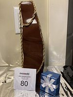 Brown necklace display stand showing bright yellow gold-tone twisted rope chain necklace with a maxsold lot number card in front.