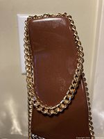 Bright 18k gold electroplated chain necklace draped over a brown display stand showing medium-thick interlocking links.