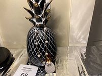 Pair of freshwater pearl drop earrings and matching necklace displayed on a black decorative pineapple stand against a neutral background.
