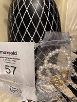 Freshwater pearl bracelet with micron gold butterfly charm in a sheer white drawstring pouch on a black and white textured background.