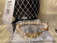 Close-up view of the freshwater pearl bracelet highlighting the crystals on the crescent moon pendant and gold clasp.