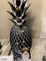 Full view of freshwater pearl necklace and earrings hanging on black decorative pineapple. Pearls are creamy white and the chain is gold-tone.