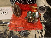 Copper wire handcrafted bracelet and adjustable ring set with natural stones displayed on a red fabric pouch and surrounded by a black and white decorative vase.