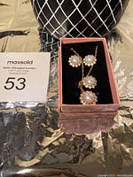 Full jewelry set in a pink box showing necklace, earrings, pendant, and ring