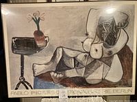 Full view of signed print depiction of reclining figure and table with vase and flowers, with text at the bottom.