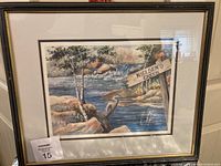 Framed watercolour painting showing the full artwork with a creek, rocks, trees, a heron, and a wooden "NIELSEN'S CREEK" sign.