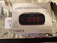 Front view of the box showing the Timex AM/FM clock radio with digital tuning, large red LED time display at 10:09, and box details.