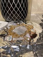 Image showing close-up of the tricolour charm bracelet laid flat with various charms visible including pearls and metallic hearts.