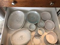 Drawer with various glass covered baking dishes and multiple white ceramic ramekins in different sizes
