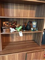 Full view of wooden shelving with display of lot items including wooden box, figurines, coasters, and decorative pieces