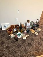 Wide view of the lot items including vases, candles, candle holders, decorative beads, and other small decor items arranged on carpet.