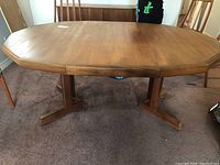 Full room view of teak dining table with two pedestal base and five chairs