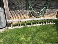 Photo of the 14-foot aluminum extension ladder laid flat on grass, showing one section of the ladder with visible rungs and top after mounting hooks.