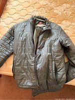 Grey Columbia Omni-Heat jacket laid on bed showing front