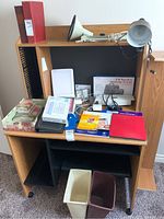 View of desk containing various office items including photo albums, an e-reader, lamp, folders, and office accessories.