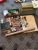 Sewing machine in olive green carrying case, assortment of sewing threads and additional accessories in boxes and bags