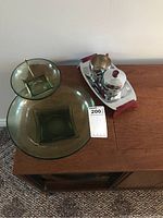 Green glass chip and dip set and stainless steel cream and sugar set on wooden surface