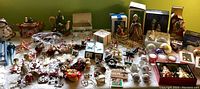 Wide top view of the table showing assorted Christmas decorations including teapots, paper ornaments, various figurines, and gift boxes.