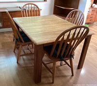 Farmhouse dining table surrounded by four chairs, showing the side and front view.