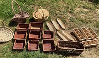 Image showing a variety of wicker and woven baskets of different shapes and sizes arranged on grass, including square, oval, divided, and picnic baskets.
