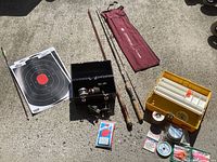 Full view of lot items including fishing poles, tackle box, reels, targets, fishing line, and accessories.