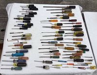 Overall view of the large assortment of screwdrivers and socket drivers laid out on white surface