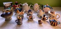 Front view of all 12 novelty teapots lined up on table