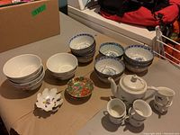 Overview of assorted bowls, small dishes and tea set pieces on table