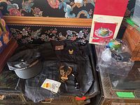 Photo showing assortment of Harley Davidson items including black leather vest, cap, pins, bottle opener, and globe ornaments with box and packaging.