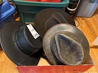 Box containing four different hats including leather and felt hats, top view showing full collection.
