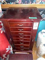 Front view of wood jewelry chest showing eight drawers with metal handles and doors on sides.