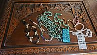 Photo of assorted semi-precious stone necklaces and bracelets laid out on a carved wooden surface