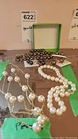 Photo showing five pearl necklaces and multiple pairs of pearl earrings, showcasing the variety of colors and styles.