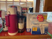 Overview photo showing four thermoses (two boxed), Trudeau tea tumbler, and Brita water pitcher with filter boxes