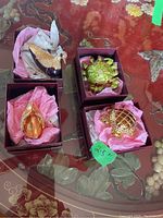 Four animal-shaped trinket boxes in boxes on a decorative surface.