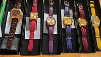 Overview of six Joan Rivers watches displayed in individual boxes with various colored straps and gold-tone cases.