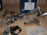 New Weiser Halifax Satin Chrome entry handleset components laid out including lever handle, latch, strike plate, keys, and mounting hardware.