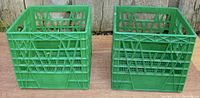 Front view of two green Neilson milk crates side by side showing the lattice design and overall structure
