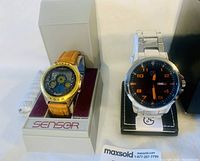 Both watches shown side by side in their original boxes, including the Sensor Moon Graph watch with leather strap and the George stainless steel watch with metal bracelet.