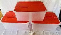 Three heavy duty plastic storage containers stacked, red lids visible, translucent bodies.