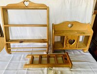 Three handcrafted wooden racks with heart designs arranged on a white surface, showing front views of each.