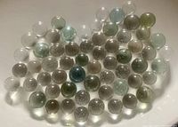 Top-down photo showing 60 clear vintage glass marbles with various sized air bubbles inside and subtle color variations from clear to pale greens and blues.