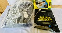 Untested Intex air mattress in blue folded form and Solar Shower bag with packaging showing 'Hot Water From The Sun' text.