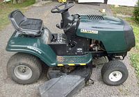 Left side profile of tractor showing seat, steering wheel, engine shroud, cutting deck and rear wheel
