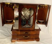 Open jewelry box with side doors opened revealing brass necklace hooks, velvet-lined ring organizer, and two drawers beneath